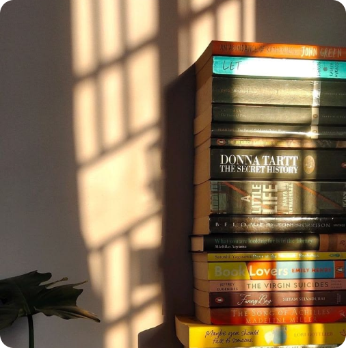 A curated stack of books in warm window light